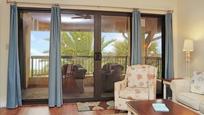Una habitación con puerta de vidrio corredera que da a un balcón con mobiliario exterior.
