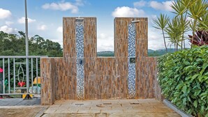 A modern outdoor area with a stone pathway leading to a wooden wall with vertical blue and white tiles. - Zuma Villa/3BR/3.5BA/Rooftop Terrace/Sea View/Pool/Gated/10 mins to Beach/Swings (Ocho Rios)