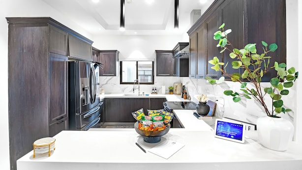 A modern kitchen with dark wood cabinets, a white countertop, and a bowl of snacks. - Zuma Villa/3BR/3.5BA/Rooftop Terrace/Sea View/Pool/Gated/10 mins to Beach/Swings (Ocho Rios)