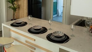 Una cocina moderna con una isla central, luces colgantes y vistas a otra habitación.