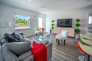 Una sala de estar moderna con un sofá, una mesa de centro de vidrio, un televisor y plantas decorativas.