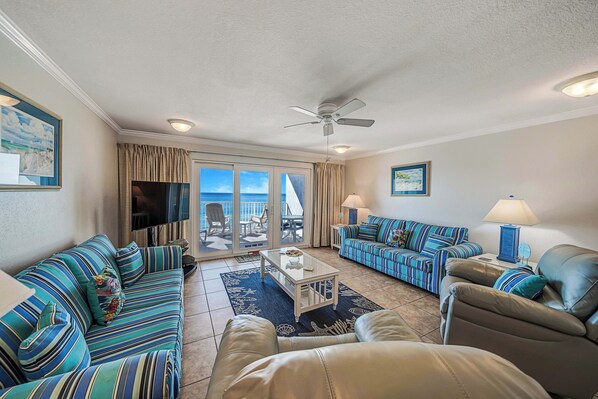 A living room with striped sofas, a coffee table, and a ceiling fan.