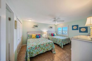 A bedroom with two beds, a ceiling fan, and a window with blinds. - FREE Golf & Perks! Mariner West 609 Beachfront Swimming Pool, Tennis, Grills! (Panama City Beach)
