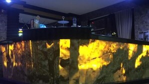 Un área de recepción con mostrador curvo de mármol, iluminación en el techo y una pared de piedra.