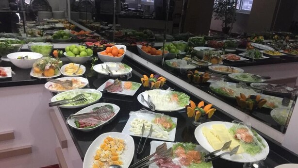 Un bufé con diversas opciones de comida, incluyendo ensaladas, frutas y carnes.