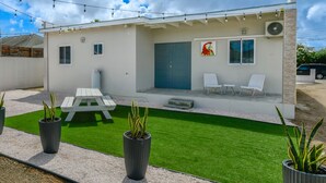 Une maison moderne dotée d’un patio, d’une pelouse artificielle et de plantes en pot.