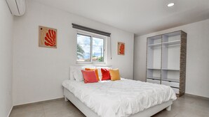 Une chambre à coucher comprenant un lit, une fenêtre, une armoire et deux œuvres d’art murales.