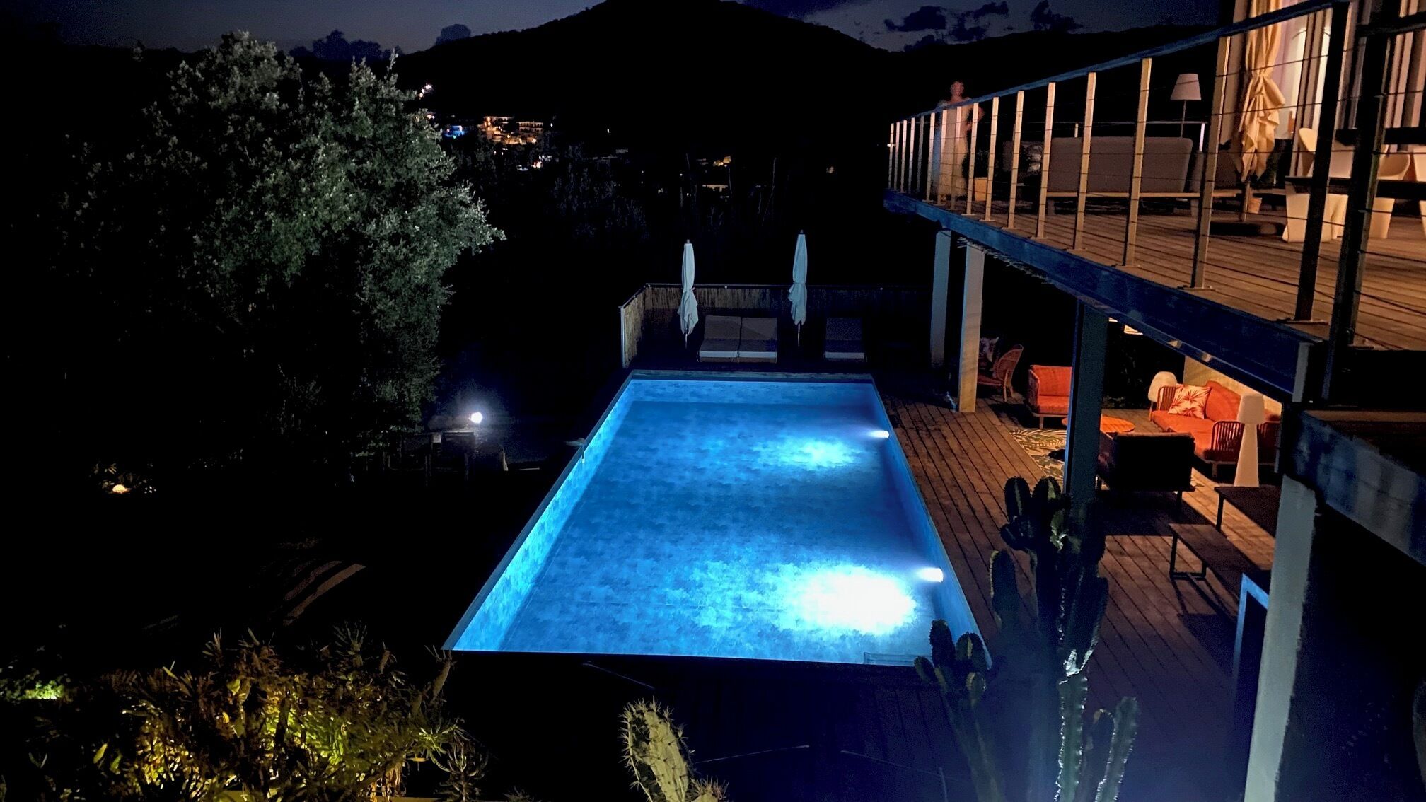 Ein Schwimmbecken mit Holzterrasse und Sitzgelegenheiten im Freien.