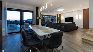 Un salon moderne comprenant un coin repas, un grand téléviseur et une vue sur l’extérieur.