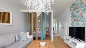 A modern living room with a grey sofa, a wooden coffee table, and a TV on a white stand. - Langgarten - Little Heaven Apartamenty (Gdansk)