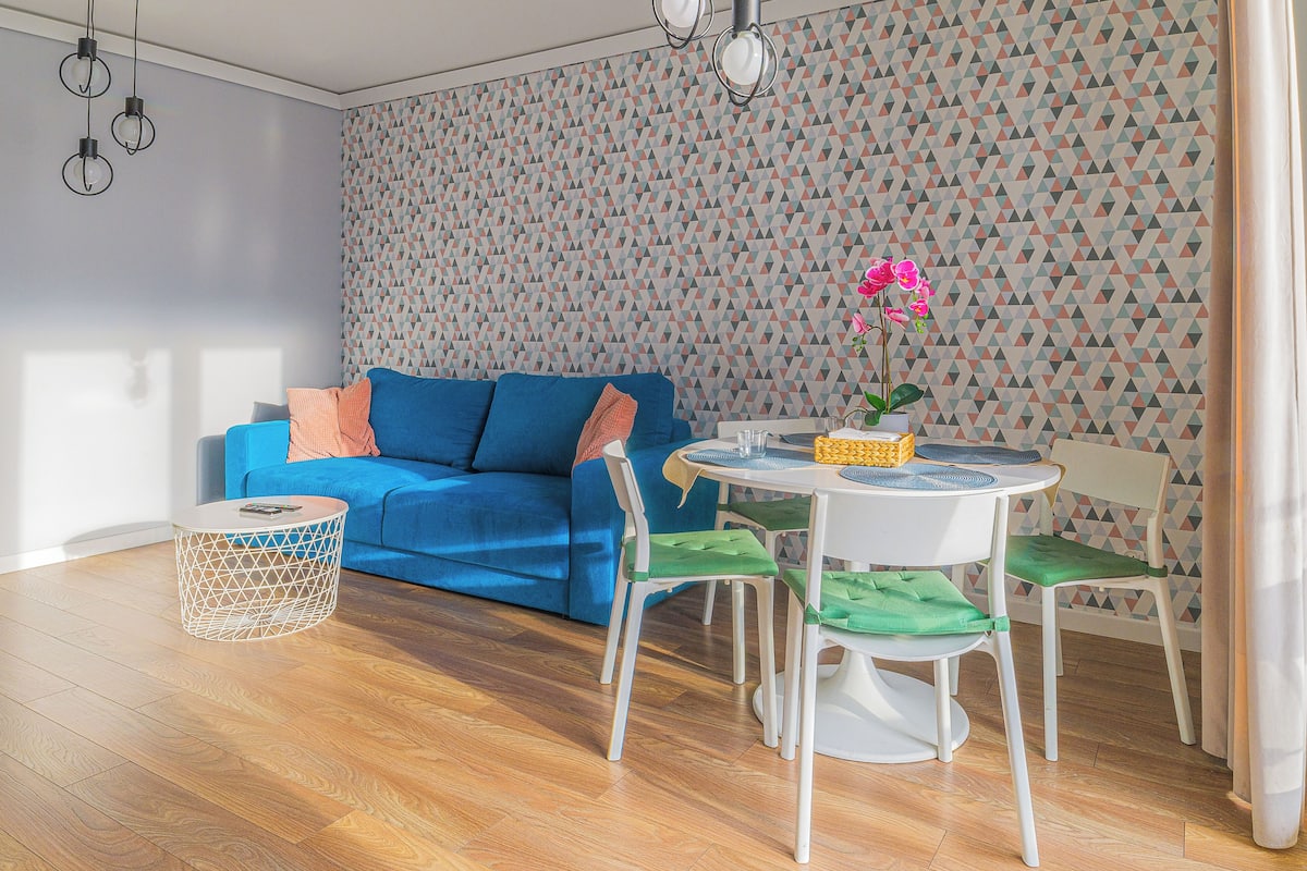 Un soggiorno moderno con un divano blu, un tavolino rotondo e carta da parati decorata.