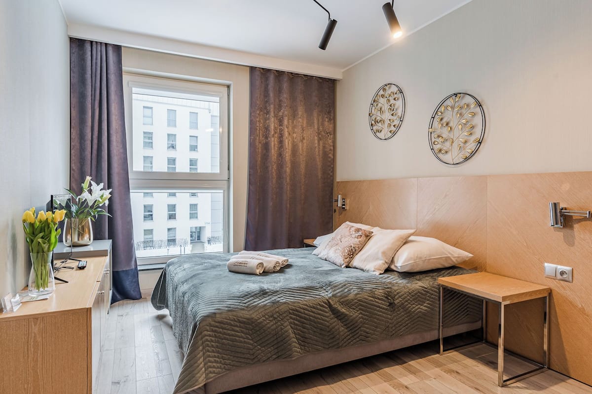 Una camera da letto moderna con un letto grande, un comodino, una scrivania e una finestra con tende.