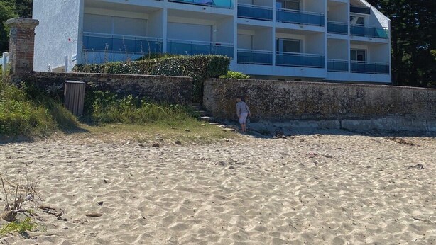 En bygning med flere etager og balkoner, beliggende ved en sandstrand.
