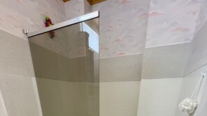 Et badeværelse med toilet, bruseniche og badekar.