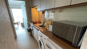 Et kompakt køkken med vaskemaskine, mikrobølgeovn og vask.