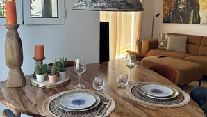 A dining area with a wooden table set for two, surrounded by chairs.