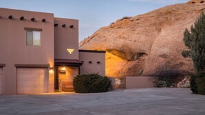 A building with a garage, a patio, and a large rock formation. - Nestled in Towering Slickrock with Private Hot Tub (Moab)
