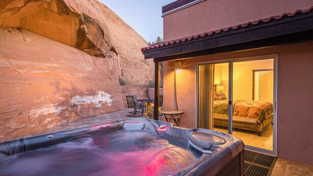 A hot tub in a backyard with a view of a bedroom through a glass door. - Nestled in Towering Slickrock with Private Hot Tub (Moab)