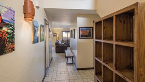 A hallway with tiled flooring, a wooden bookshelf, and a sofa in the background. - Nestled in Towering Slickrock with Private Hot Tub (Moab)