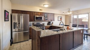 A modern kitchen with stainless steel appliances, a granite countertop, and wooden cabinets. - Nestled in Towering Slickrock with Private Hot Tub (Moab)