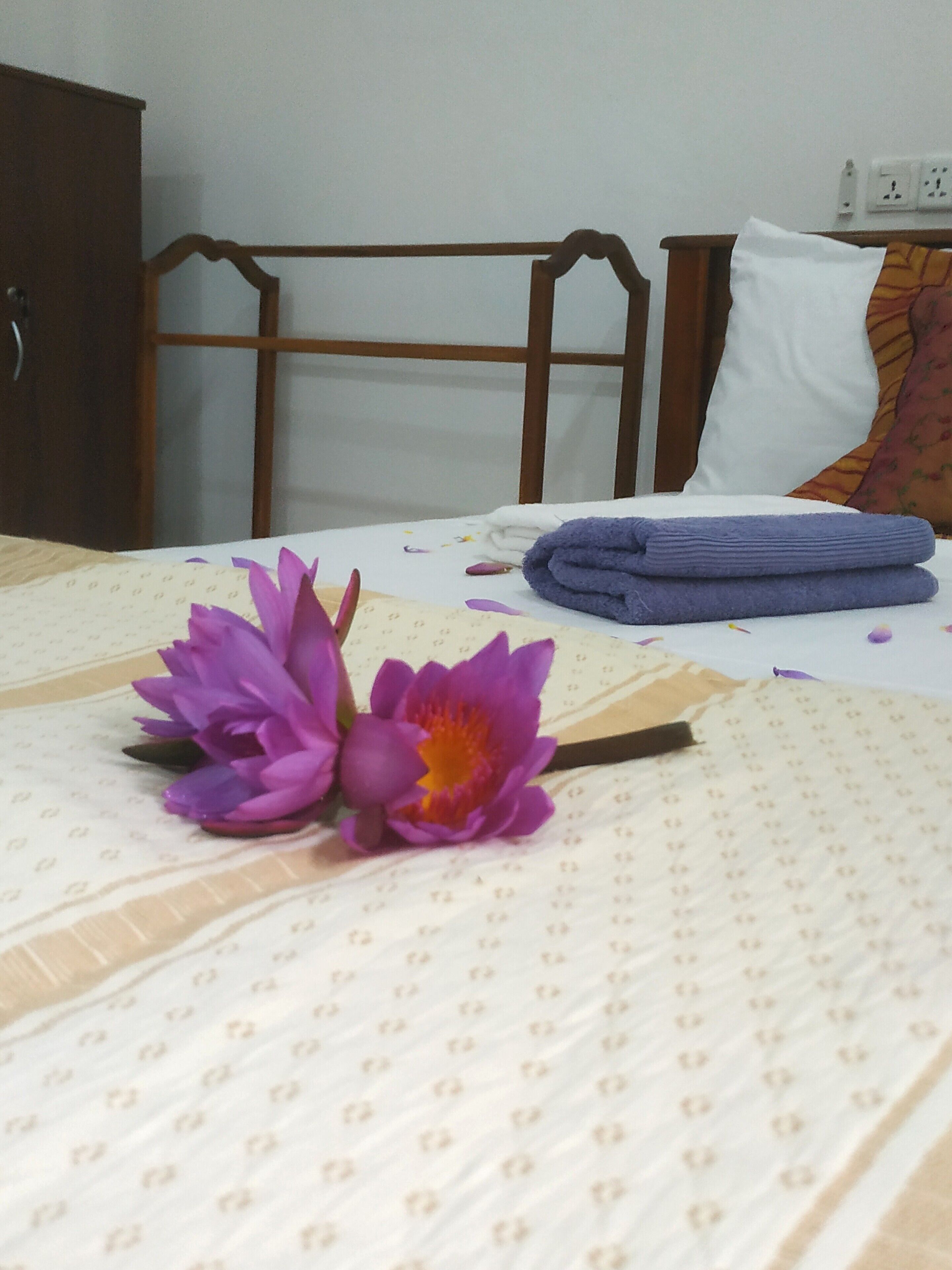 A bed with a patterned bedspread, a wooden headboard, and a pillow with a colorful blanket.
