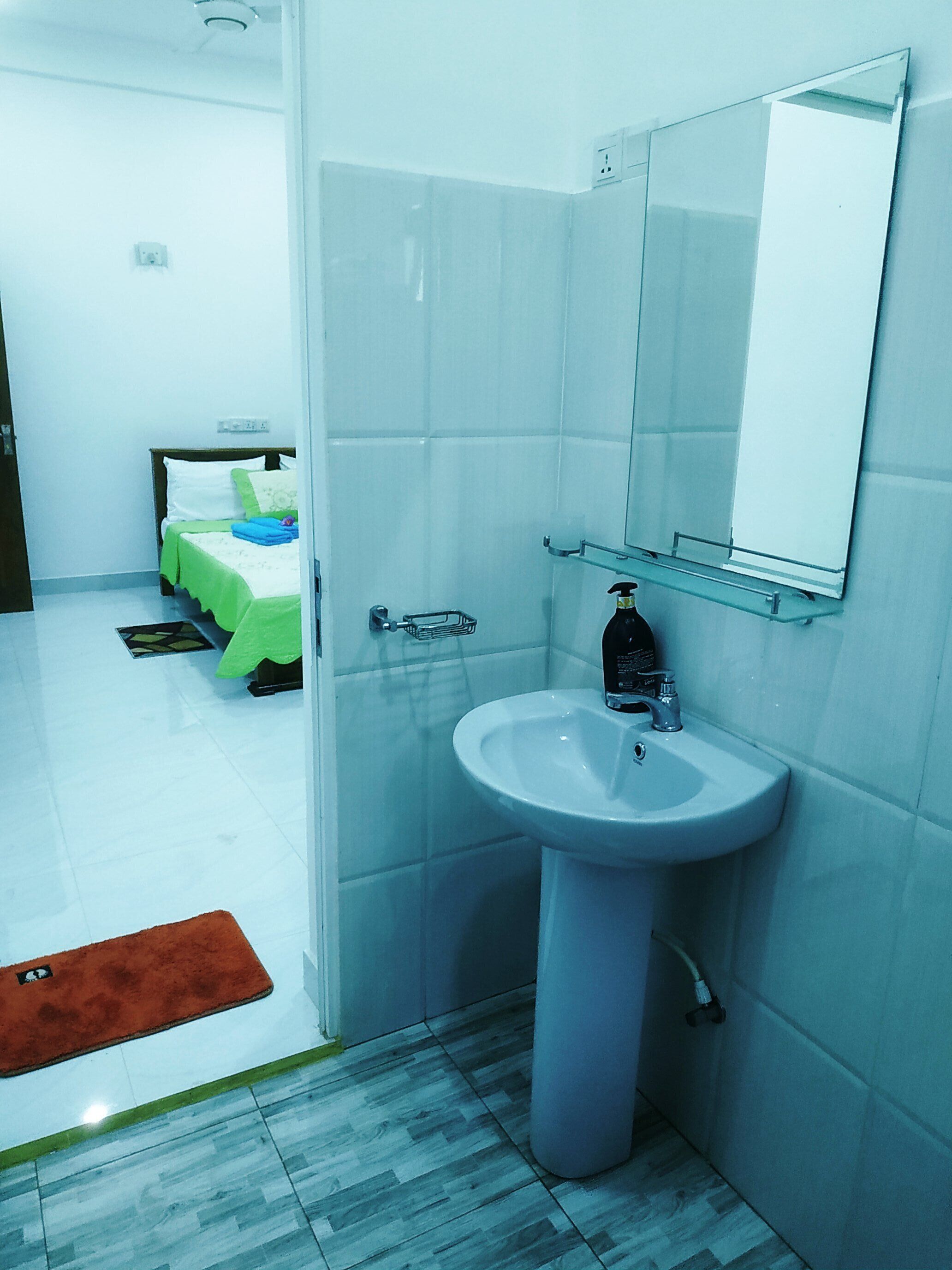 Une salle de bain avec un lavabo blanc, un miroir et un espace douche.