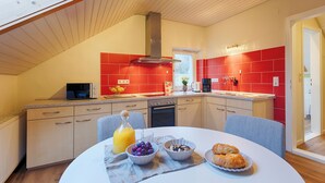 Una cucina moderna con piastrelle rosse, un forno a microonde e un'area pranzo con prodotti per la colazione.