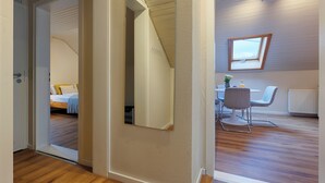 Una stanza moderna con pavimento in legno, un letto con testiera bianca, un'area pranzo con tavolo e sedie e un lucernario.
