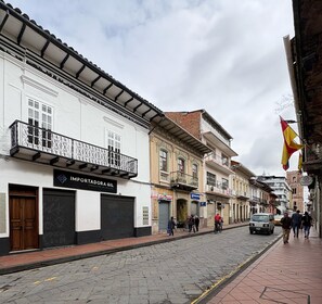 A cobblestone street lined with historic buildings, including a white building with a black storefront and a sign reading "IMPORTADORA GIL." - House with 5-bedroom 5 bathrooms  in charming Colonial Cuenca Center - Casa 621 (Cuenca)