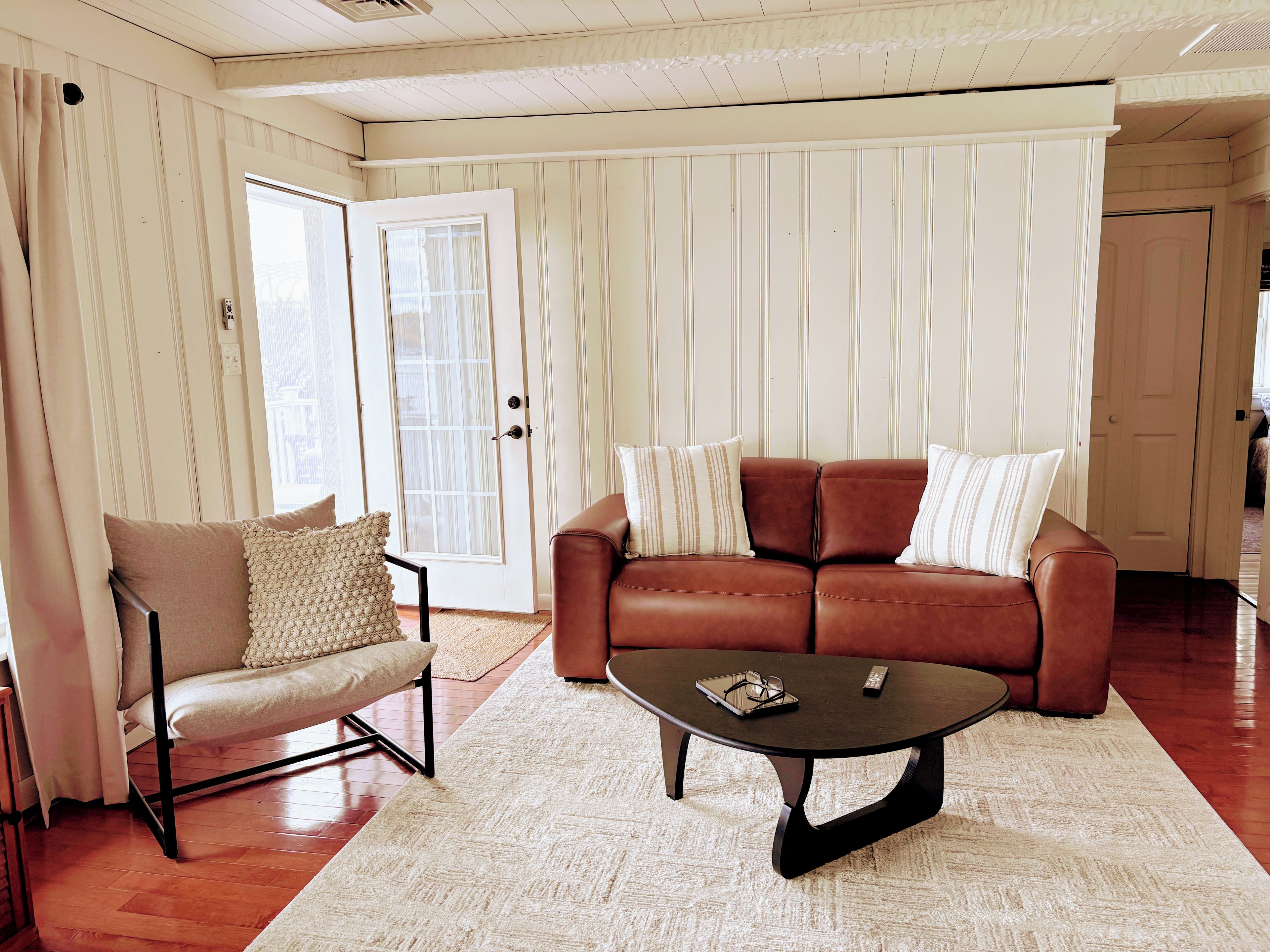 A living room with a brown leather sofa, a white armchair, and a coffee table.