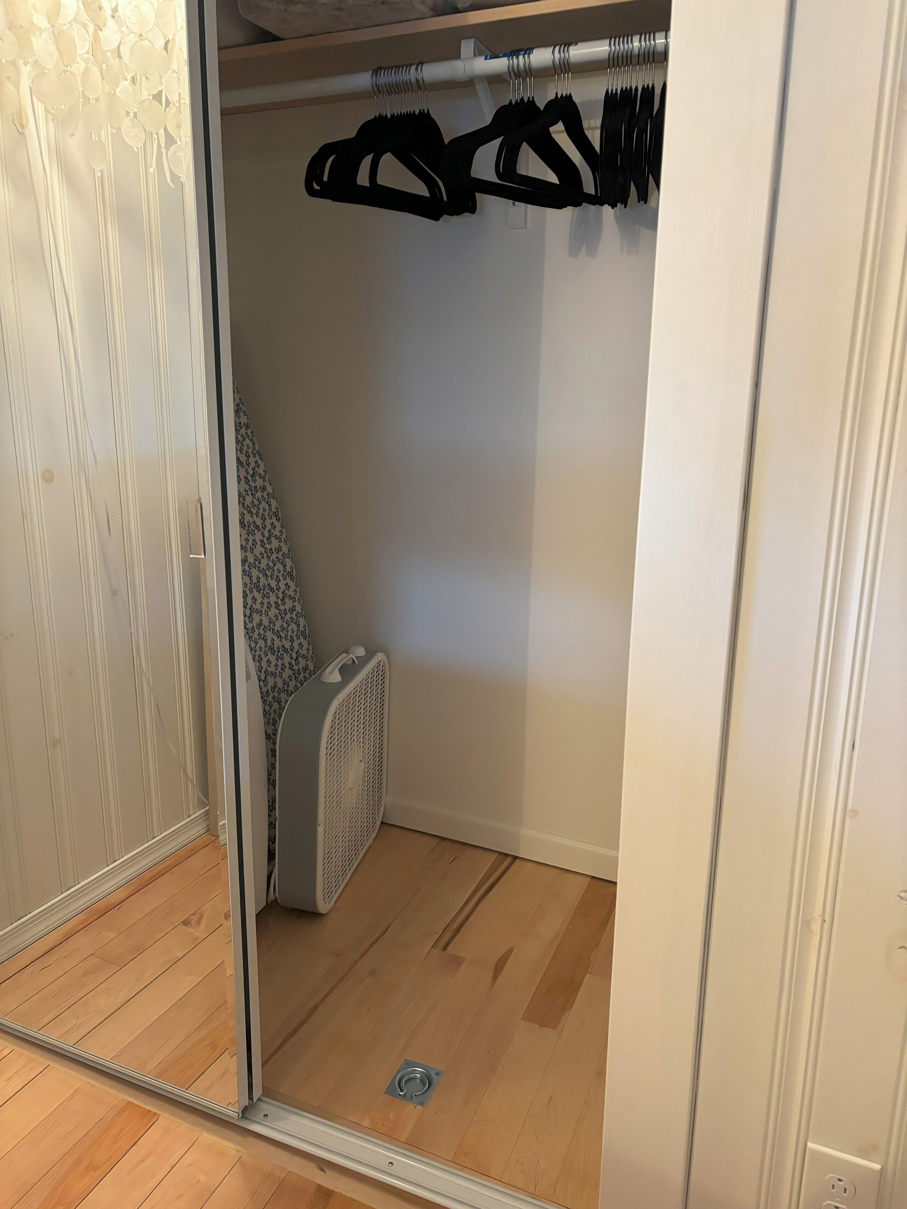 Ein begehbarer Kleiderschrank mit einer Spiegel-Schranktür, einem Heizkörper und einer weißen Wand.