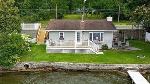 Una casa a un piano con veranda anteriore, un piccolo portico e un pontile che si protende sull'acqua.