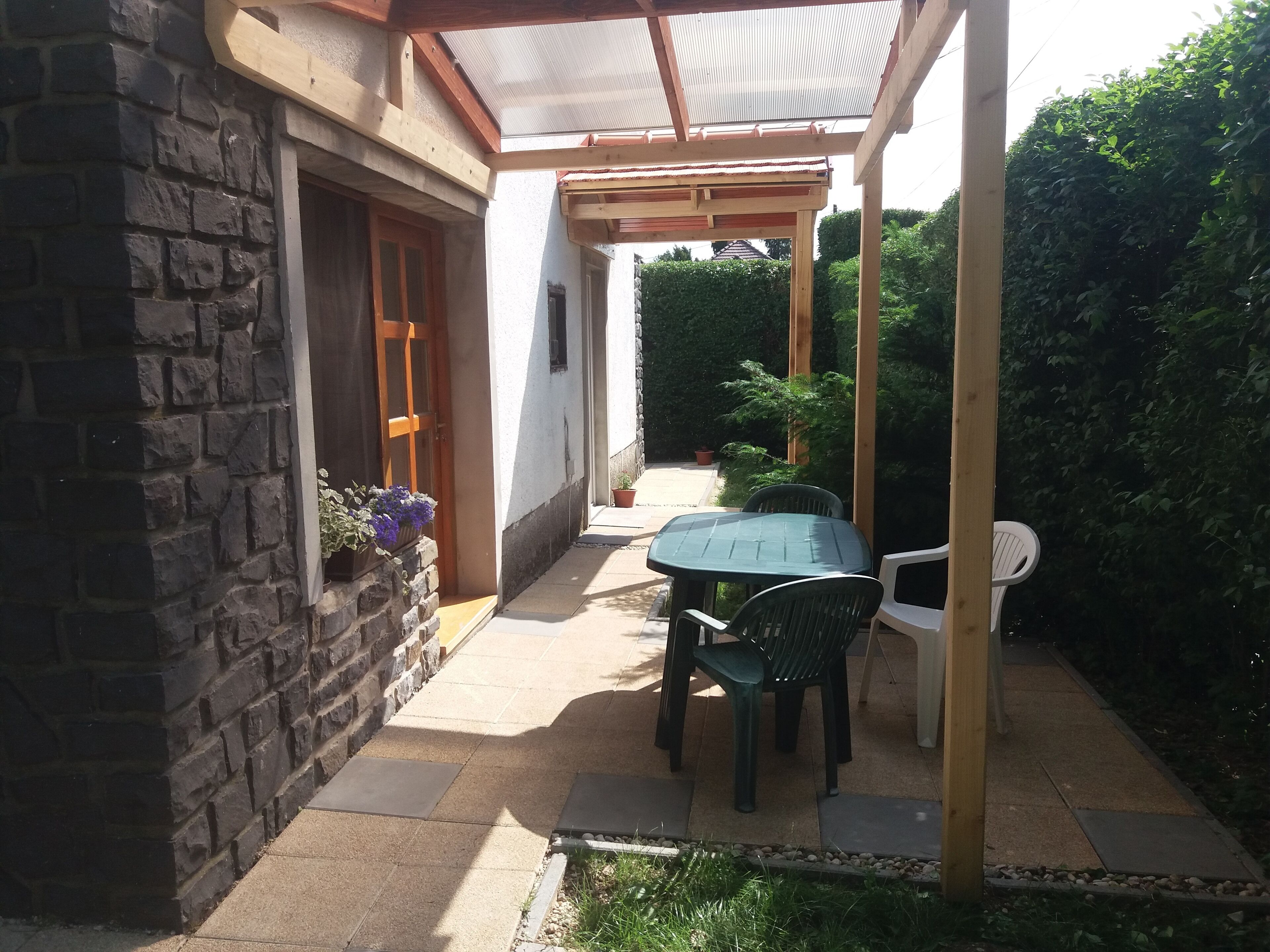 A patio with a table and chairs, a wooden door, and a stone wall.