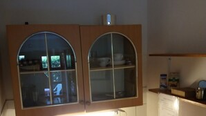 A kitchen with a double sink, a window above the sink, and a shelf with items.