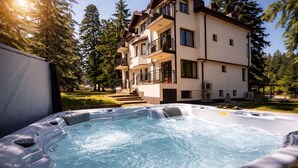 A hot tub with a view of a multi-story building and surrounding trees. - Villa Rila in Borovets (Samokov)