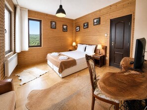A hotel room with a wooden wall, a large bed, two bedside tables with lamps, a television, and a view of the outdoors. - Villa Rila in Borovets (Samokov)