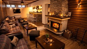 A cozy living room with a fireplace, a sofa set, a dining area, and a kitchen in the background. - Villa Rila in Borovets (Samokov)