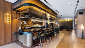 A modern bar area with a counter, bar stools, and a seating area with tables and chairs. - Luxury Condos in Downtown Miami (Miami)