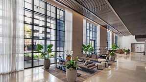A spacious lobby with large windows, a seating area with sofas and armchairs, and several potted plants. - Luxury Condos in Downtown Miami (Miami)