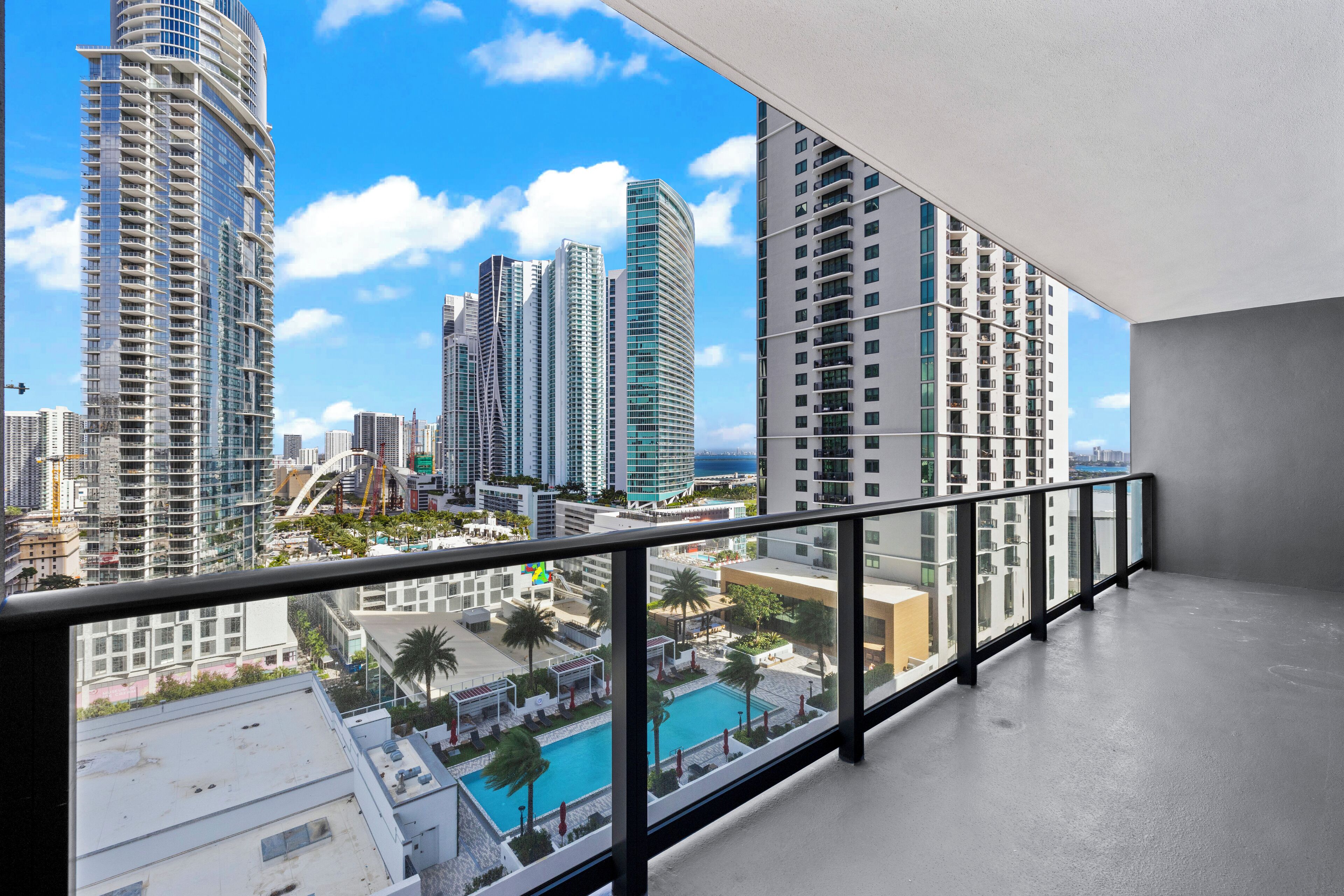 Un edificio de gran altura con un diseño moderno, que presenta un amplio frente de vidrio y una piscina en la azotea.