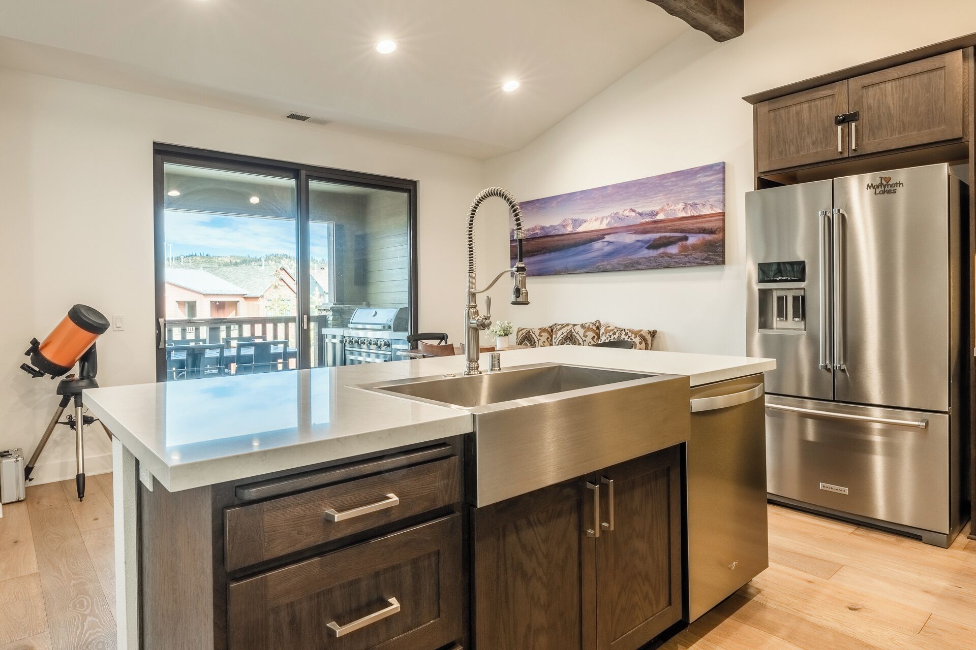 A modern kitchen with a stainless steel refrigerator, a built-in dishwasher, and a large island with a sink.