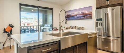 A modern kitchen with a stainless steel refrigerator, a built-in dishwasher, and a large island with a sink.