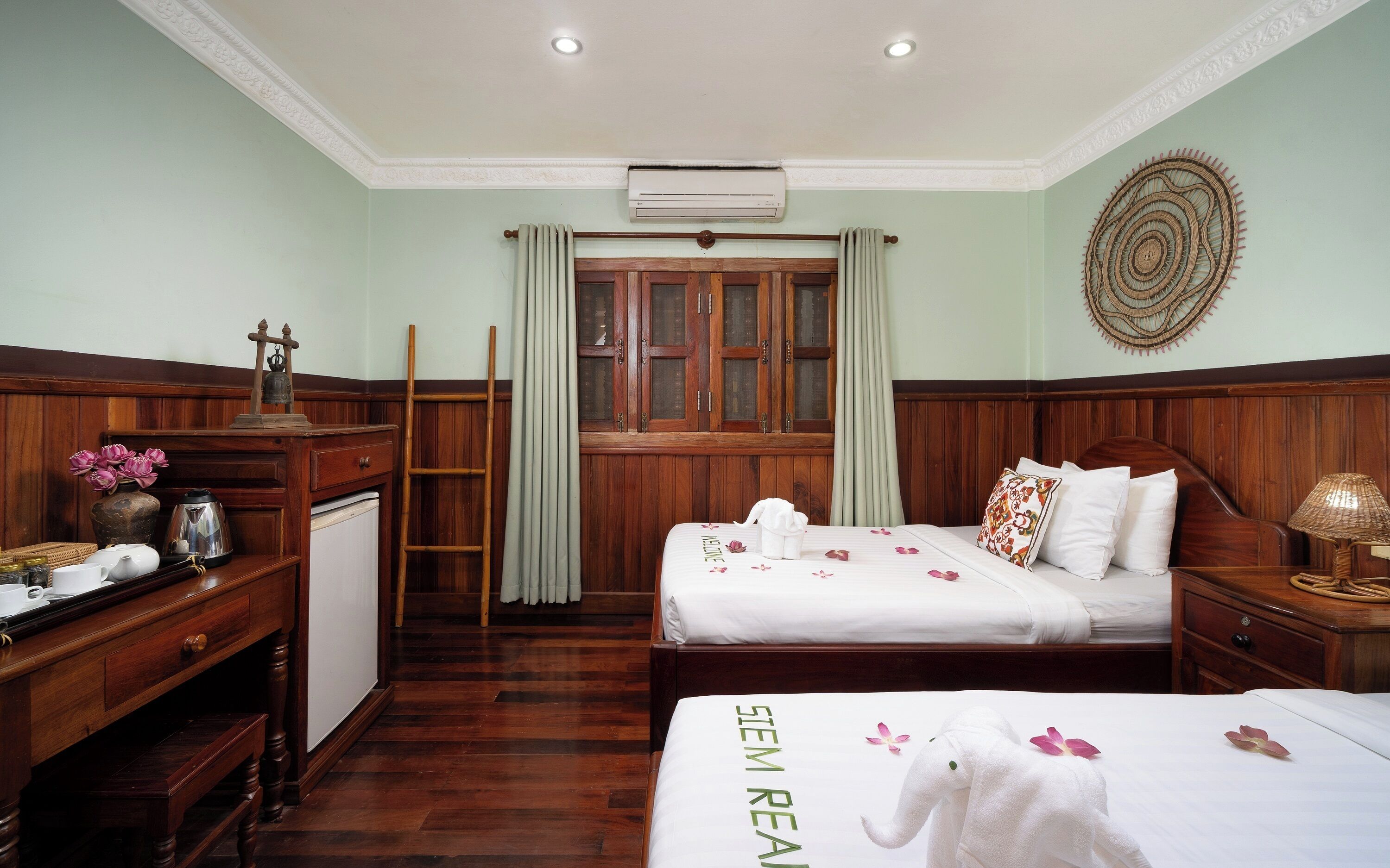 Habitación de hotel con dos camas, un escritorio, un armario, una ventana con cortinas y un equipo de aire acondicionado.
