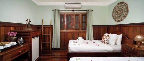 Habitación de hotel con dos camas, un escritorio, un armario, una ventana con cortinas y un equipo de aire acondicionado.
