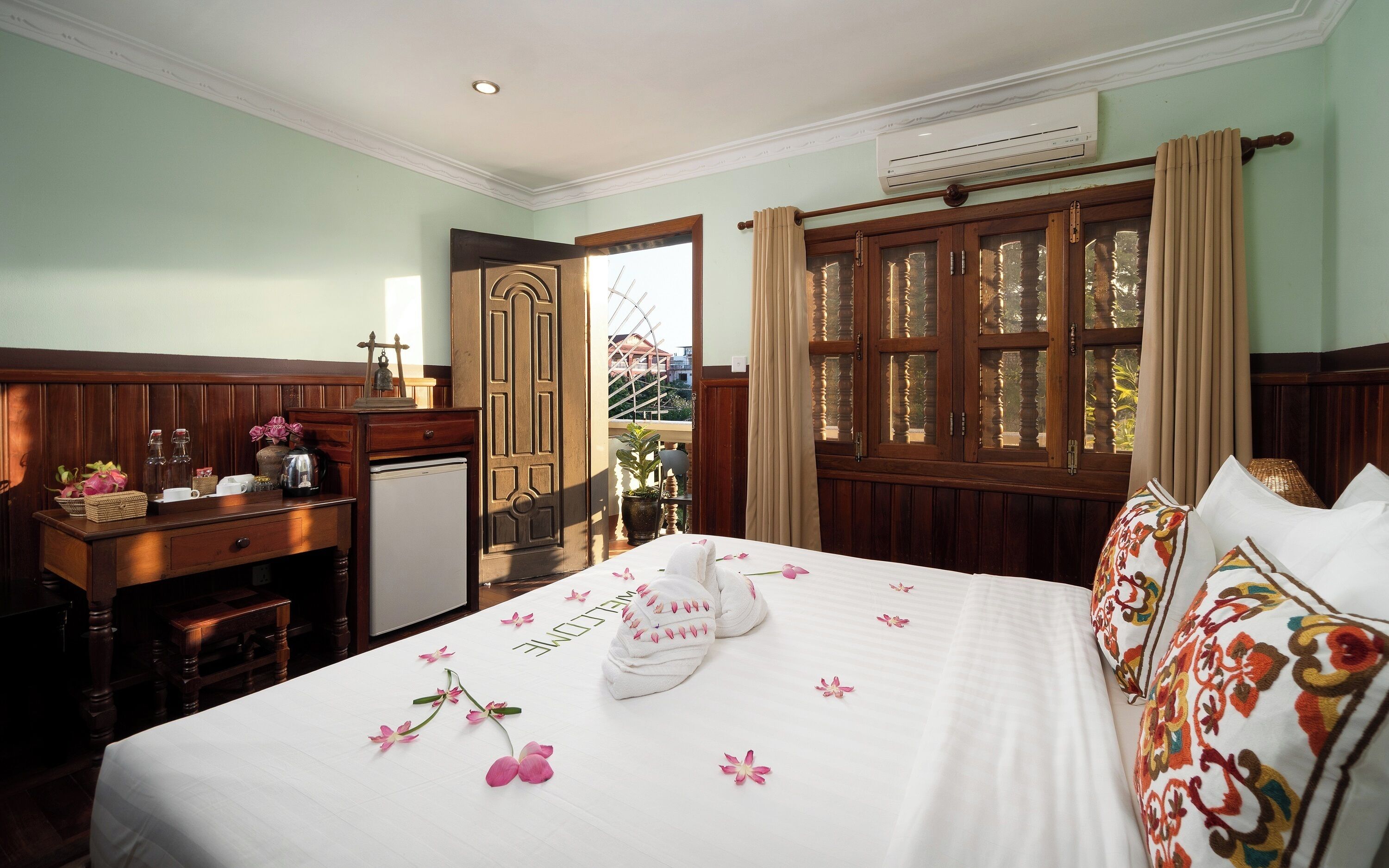 A hotel room with a bed, a desk, a small refrigerator, and a window with curtains.