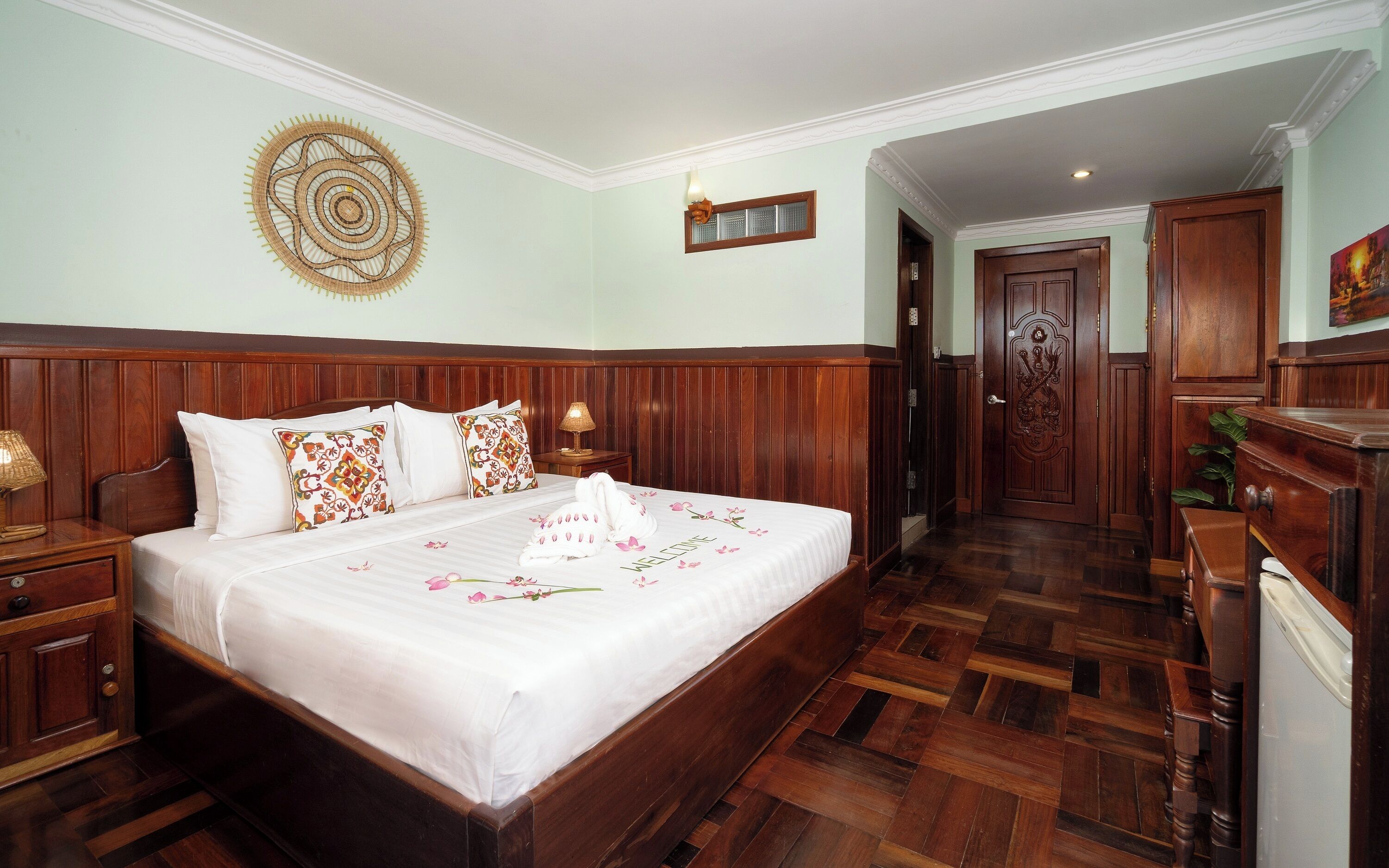 Una habitación de hotel con una cama grande, cabecera de madera y un tapiz decorativo.
