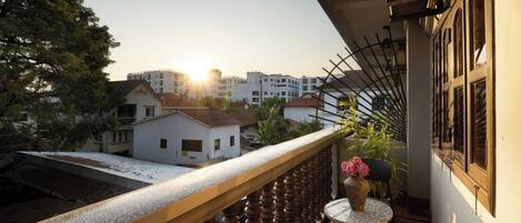 A balcony with a view of a residential area, a small table with a vase, and a chair.