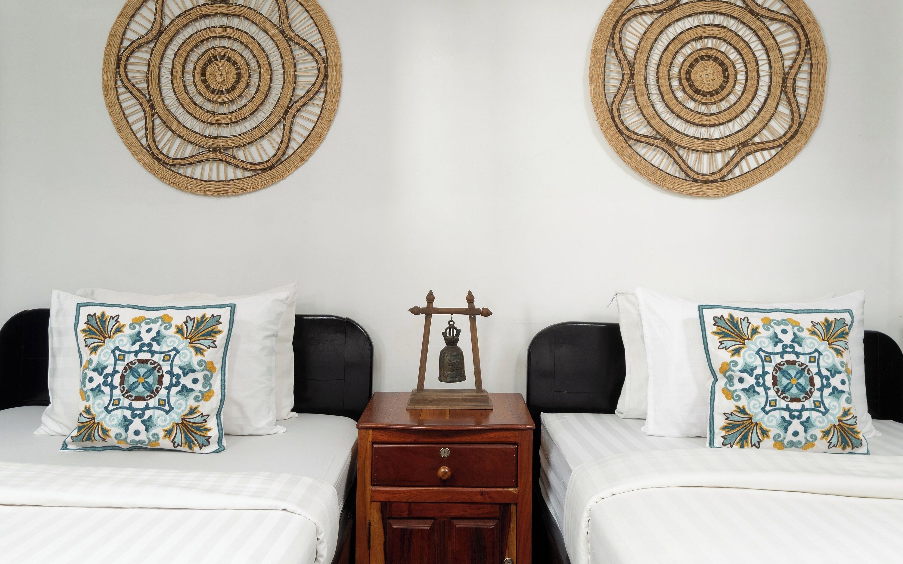 A hotel room with two beds, a nightstand, and two decorative wall hangings.