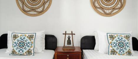 A hotel room with two beds, a nightstand, and two decorative wall hangings.