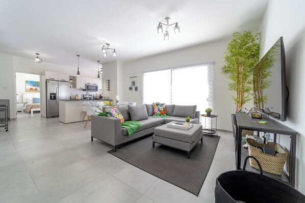 A modern living room with a grey sofa, a coffee table, and a large window.